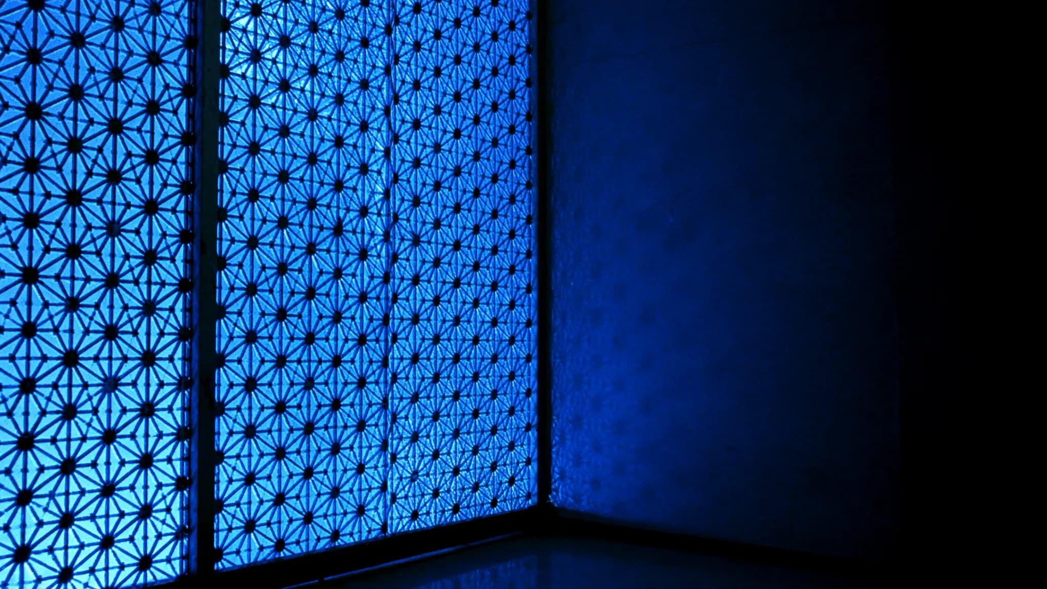 A Qatari mashrabiya screen with azure light coming through its lattice